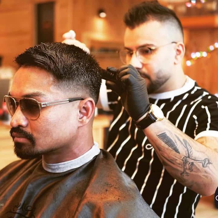 Mokhaled klipper en kunde i barbershoppen